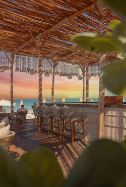 Idyllic Beach Bar at Saadiyat Beach Club set against a striking pastel sunset sky over the Abu Dhabi coastline.