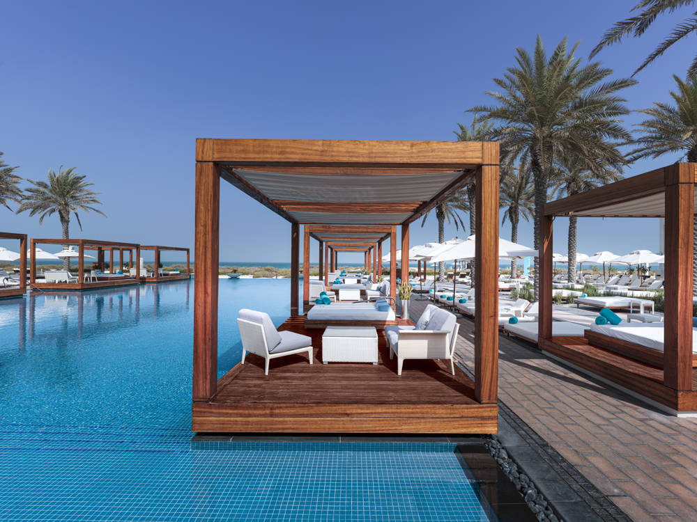 Floating cabana in the pool at Saadiyat Beach Club, surrounded by palm trees under clear Abu Dhabi skies.