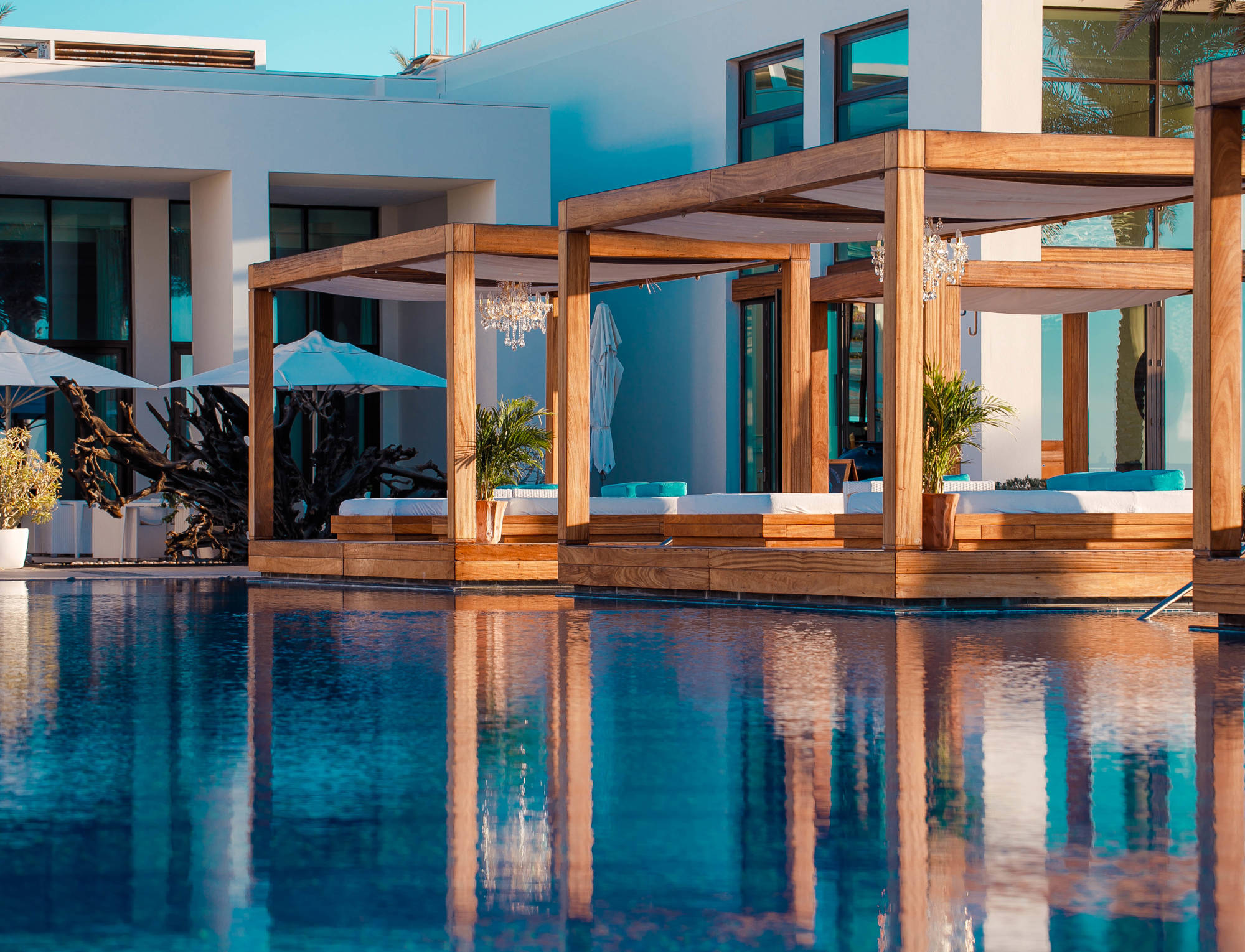 Floating cabanas mirrored in the still pool at Saadiyat Beach Club, creating a serene and elegant atmosphere.